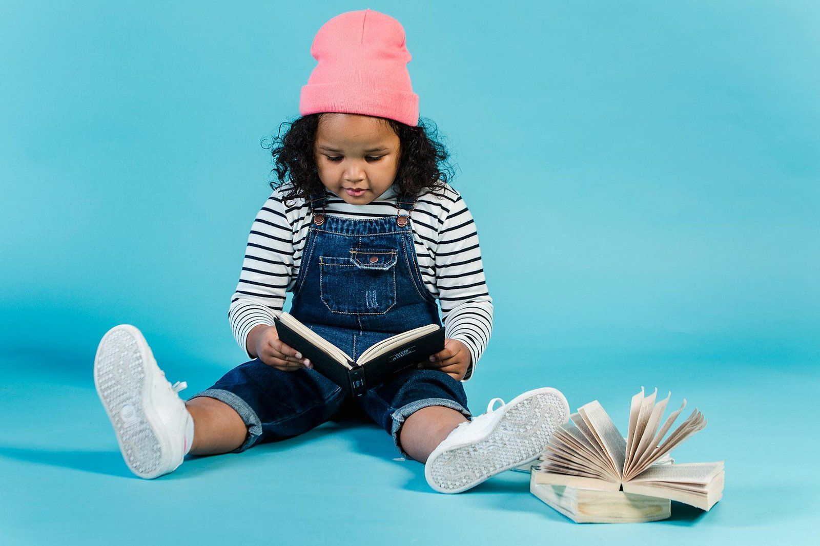 https://www.pexels.com/photo/adorable-black-girl-reading-interesting-book-5561164/